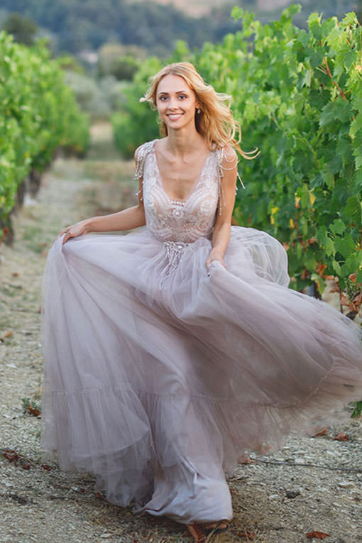 Vineyard Wedding im Elsass, Frankreich. Brautstyling. Hübsche junge Braut in einem fliederfarbenem Traum von Hochzeitskleid aus Tüll, das Oberteil mit Spitze und Perlen bestückt, läuft durch einen Weinberg zur Hochzeitszeremonie.