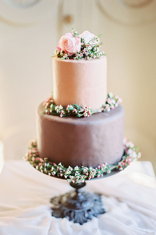Closeup of two-tier wedding cake in tender rose colors with flowers on a cake-shelf.