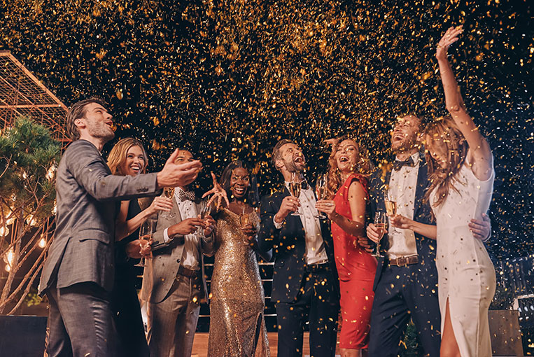 Outdoor Geburtstagsparty junger Leute in eleganter Abendgarderobe mit Champagner und Konfetti.
