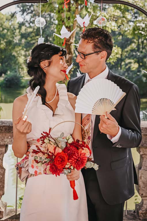 Strahlende junge Braut wirbelt ihr Hochzeitskleid tanzend in einem alten Säulengang im Grünen.